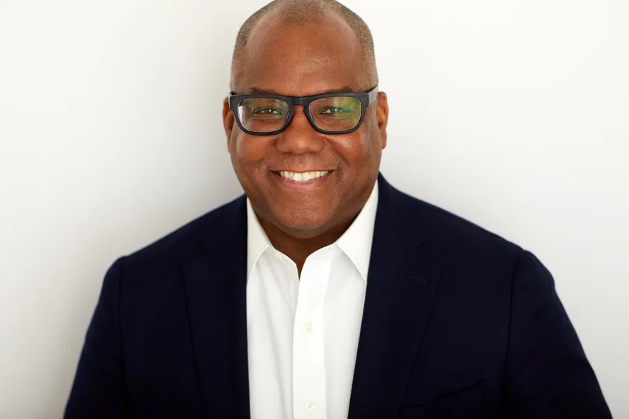 Kahlil (KB) Byrd, smiling, wearing glasses and a navy jacket
