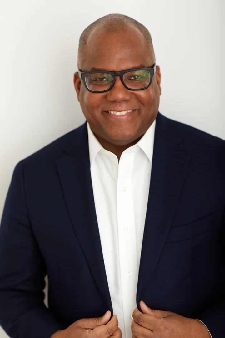 Kahlil Byrd standing in a navy jacket and open-collar white shirt