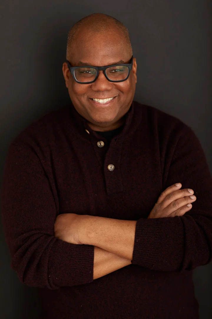Kahlil Byrd smiling with arms folded, wearing a dark sweater